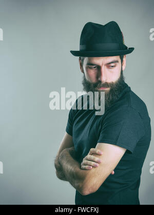 Side view of sad bearded stylish man wearing hat looking back over the shoulder. Retro style toned filtered vintage photo Stock Photo