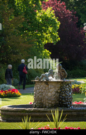 Valley Gardens, Harrogate, Yorkshire, England - beautiful, sunny tranquil park with fountain, colourful flowerbeds and 2 people relaxing and walking. Stock Photo