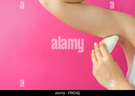 Woman epilates her armpit with an electric epilator device Stock Photo