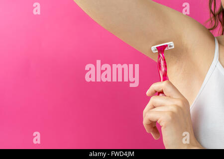 woman shaving her armpit with red shaver Stock Photo