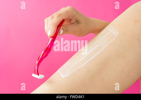 woman shaving her leg with red shaver Stock Photo