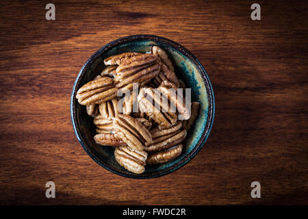 Pecans in ceramic bowl on wooden table. Shallow depth of field. Top view. Stock Photo