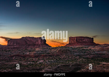 The sun sets behind the giant rock formations, Monitor and Merrimac buttes found in midwest America, Utah. Stock Photo