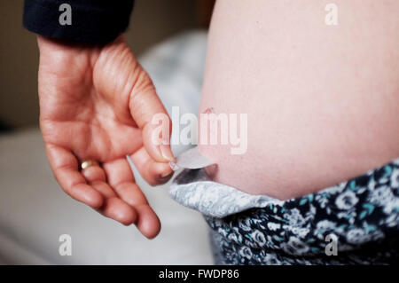 Middle aged woman using Evorel Conti HRT patches to help with the menopause Hormone Replacement Therapy treatment Stock Photo