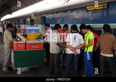 Passengers buying food and drink from a platform vendor before boarding their train at Jhansi Station, India. Stock Photo