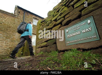 A walker passes the sign marking the official start of the Pennine Way National Trail in Edale village, Peak District Derbyshire Stock Photo
