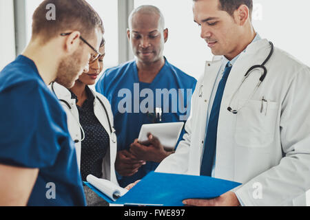 Doctors having a conversation looking at documents, mixed races, surgeons and doctors Stock Photo