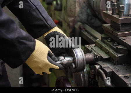worker in protective gloves in factory using machine Stock Photo