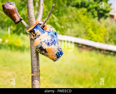 Colorful handmade and hand painted pots hanging on branches of a tree trunk. Stock Photo