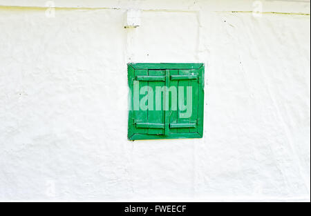 Closed green wooden window shutters on an old whitewashed wall. Stock Photo