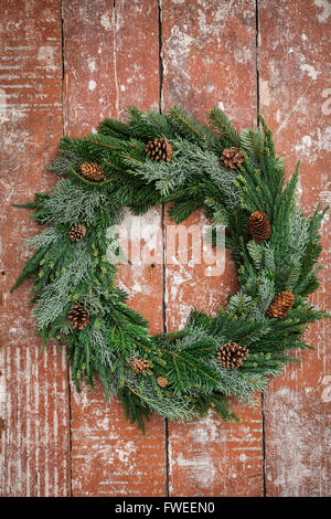 Christmas wreath of pine branches with cones on white wooden background ...
