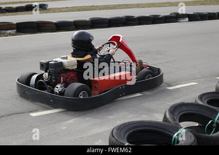 boy is driving Go-kart car with speed in a playground racing track. Go kart is a popular leisure motor sports. Stock Photo