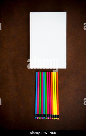 Wooden desktop with colorful pencil and white book vertical frame Stock Photo