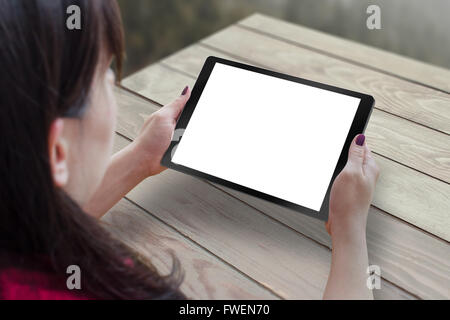Black tablet with blank, white, isolated screen for mockup in woman hand. Table in background. Stock Photo