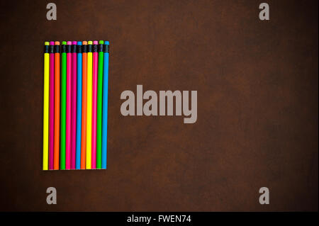Wooden desktop with colorful pencil on the left side, red yellow, blue, green and purple Stock Photo