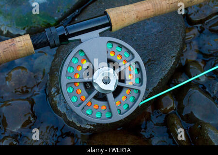 A fly fishing rod and reel sit upon some river rock on the edge of the Willamette River in Oregon. Stock Photo