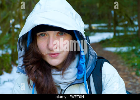 A woman pauses during her hike for a rest and to look at the camera while wearing a white jacket. Stock Photo