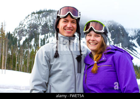 A happy couple together on the mountain resort in the snow for a day of skiing and snowboarding. Stock Photo