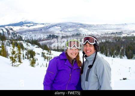 A happy couple together on the mountain resort in the snow for a day of skiing and snowboarding. Stock Photo