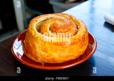 A morning bun cinnamon roll on a plate at a cafe restaurant. Stock Photo