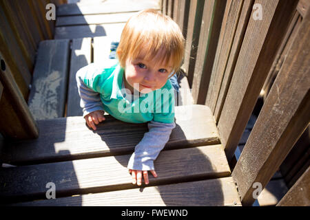 A cute young boy climbs the wooden stairs at a playground in a park in Lincoln City Oregon. Stock Photo