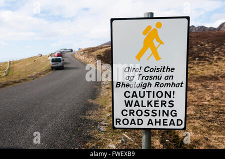 Sign in Irish and English, warning drivers that walkers are crossing the road ahead. Stock Photo