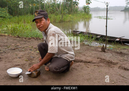 An inhabitant of the riverside village of Timicuro I sharpens a knife in front of his house. Iqutios peruvian amazon, Loreto, Pe Stock Photo