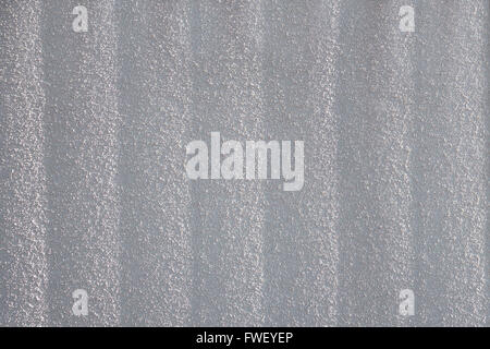 Grainy, light gray roughcast with vertical texture in sunlight. Taken in close-up. Stock Photo