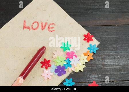 handwritten word love on paper with artificial flowers Stock Photo