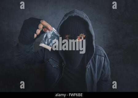 Drug dealer offering narcotic substance to addict on the street, unrecognizable hooded criminal selling drugs in dark alley Stock Photo