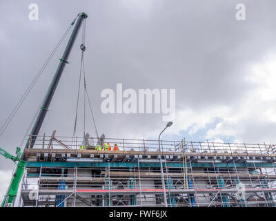 Construction workers fitting concrete pillars using a large crane Stock Photo