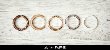 Women's rings arranged in a row on the wooden backround. Costume jewelry.