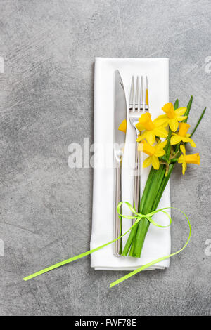 Fork, knife and napkin over table plate with spring flowers decoration Stock Photo