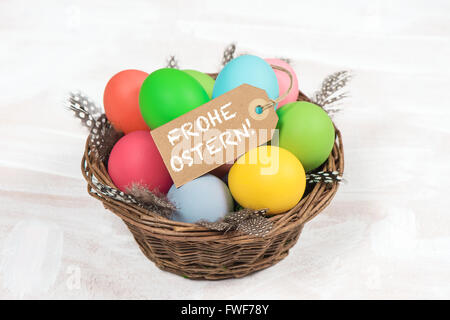 Easter eggs in basket with feather decoration. Happy Easter - Frohe Ostern germen text Stock Photo