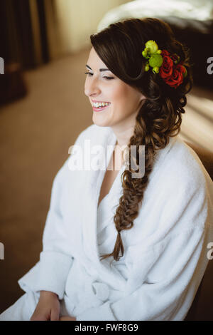 bride sits on a chair in white robe Stock Photo