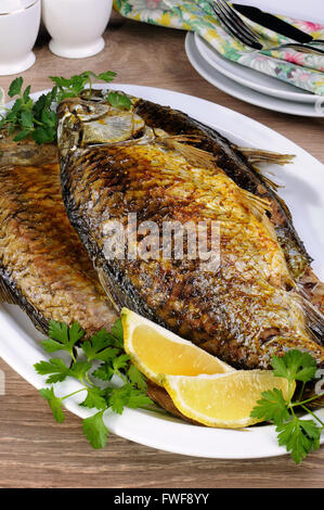 Fried crucian carp in a plate on the table  closeup