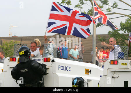 Armed police officers watch Loyalists during trouble in north Belfast after a sustained attack on police in the Woodvale area of Stock Photo