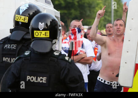 Armed police officers watch Loyalists during trouble in north Belfast after a sustained attack on police in the Woodvale area of Stock Photo