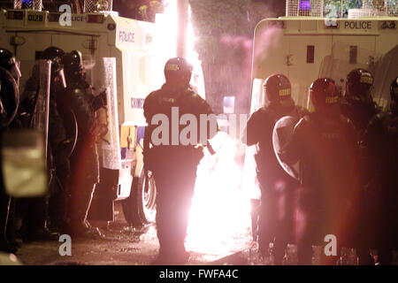 Armed police officers watch Loyalists during trouble in north Belfast after a sustained attack on police in the Woodvale area of Stock Photo