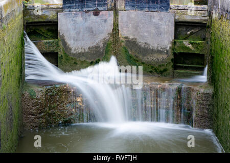 Canal lock cill with water spilling through gate. Lock with water escaping at high pressure through gaps, splashing onto cill Stock Photo