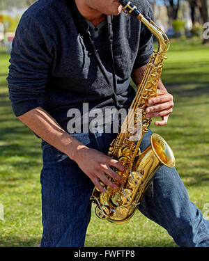 Young man playing a saxophone in the park Stock Photo