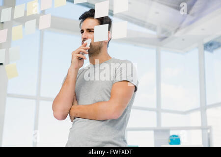 Thoughtful man looking at sticky notes on window Stock Photo