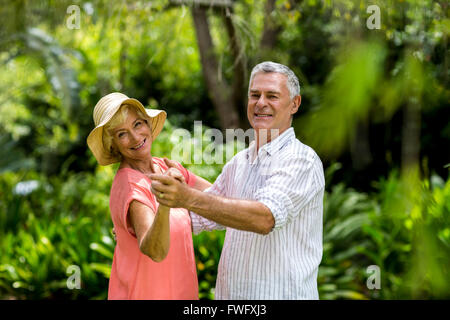 Senior couple holding hands while dancing in yard Stock Photo
