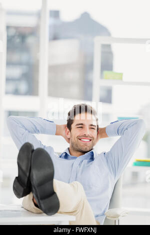 Thoughtful man sitting with feet on table Stock Photo