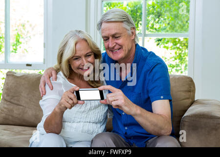 Senior couple using mobile phone while sitting at home Stock Photo