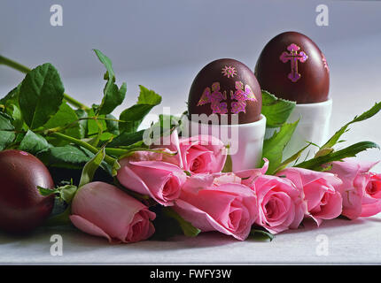 Easter still life with colored eggs in the stands and roses on the table. Stock Photo