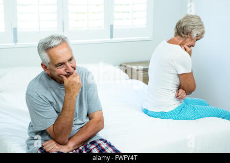 Sad senior man and woman sitting on bed Stock Photo