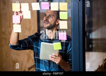 Man using digital tablet while writing on sticky notes Stock Photo