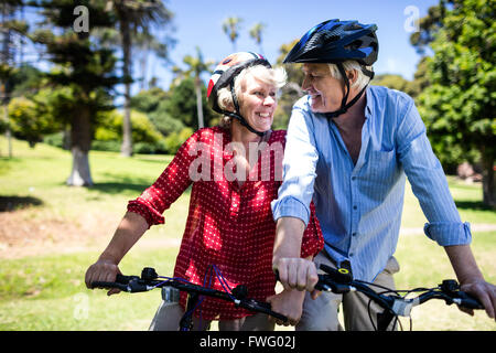 Happy couple riding a bicycle in park Stock Photo