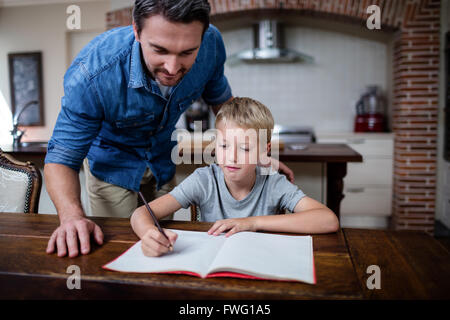 Father helping son with his homework in kitchen Stock Photo